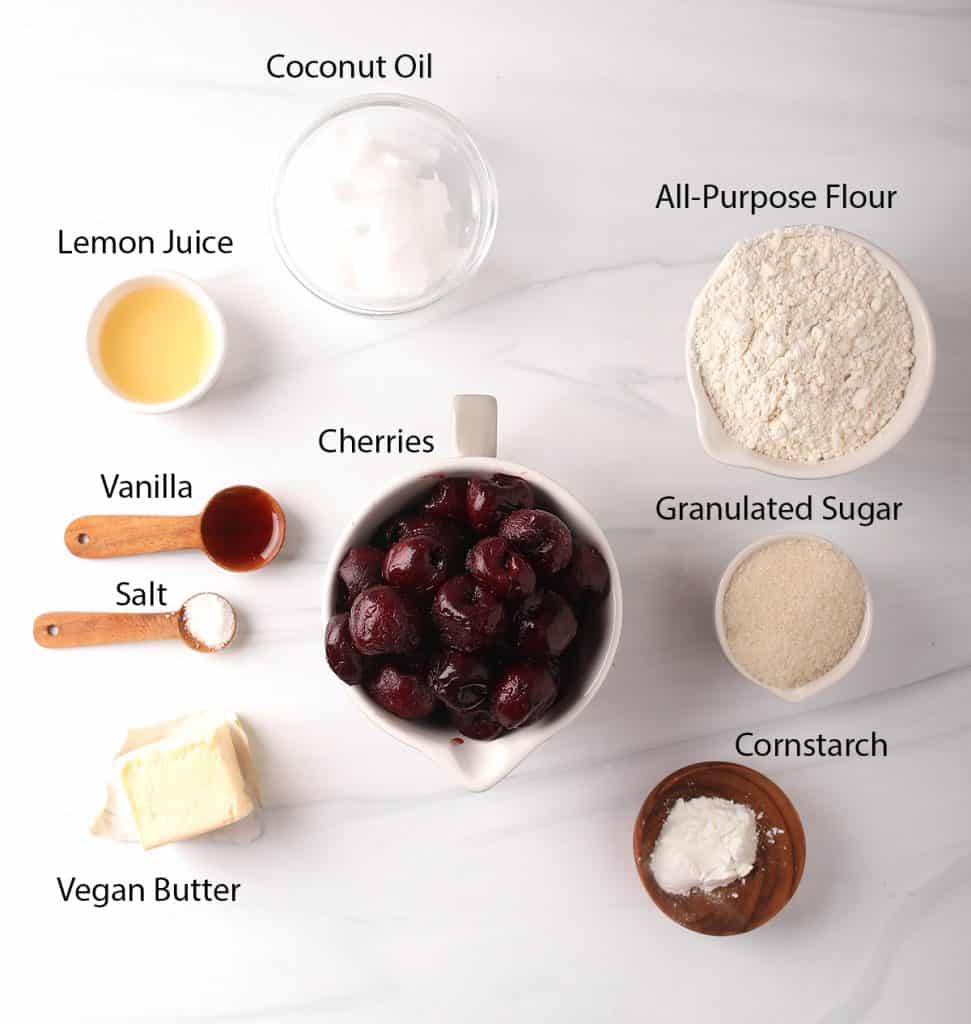 ingredients for homemade vegan cherry pies measured out into bowls on a white table
