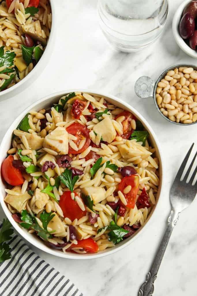 Mediterranean Orzo Salad in a white bowl with a fork next to it. 