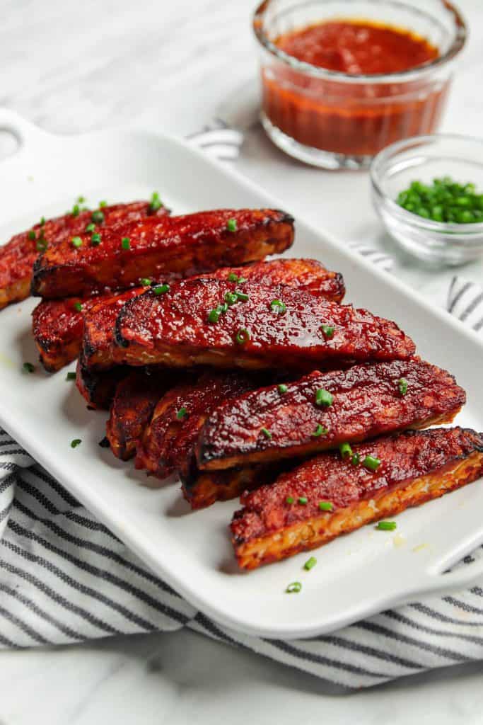 vegan BBQ tempeh served on a white plate garnished with chives