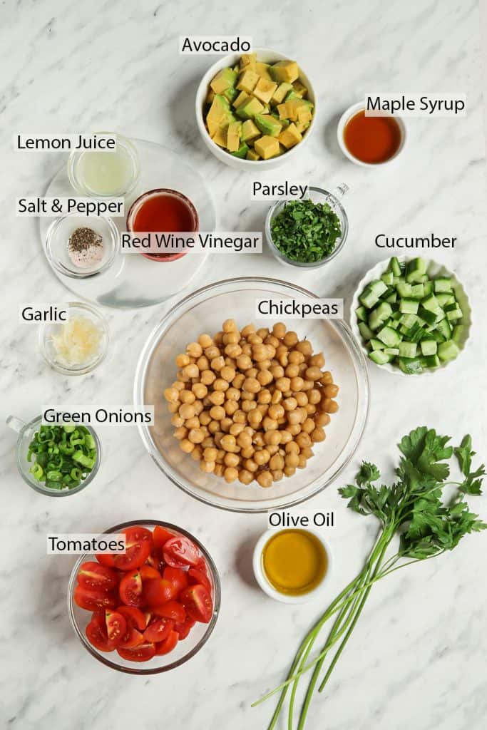 top view of olive oil, parsley, cucumbers, chickpeas, parsley, maple syrup, avocado, red wine vinegar, lemon juice, salt and pepper, garlic, green onions, and tomatoes