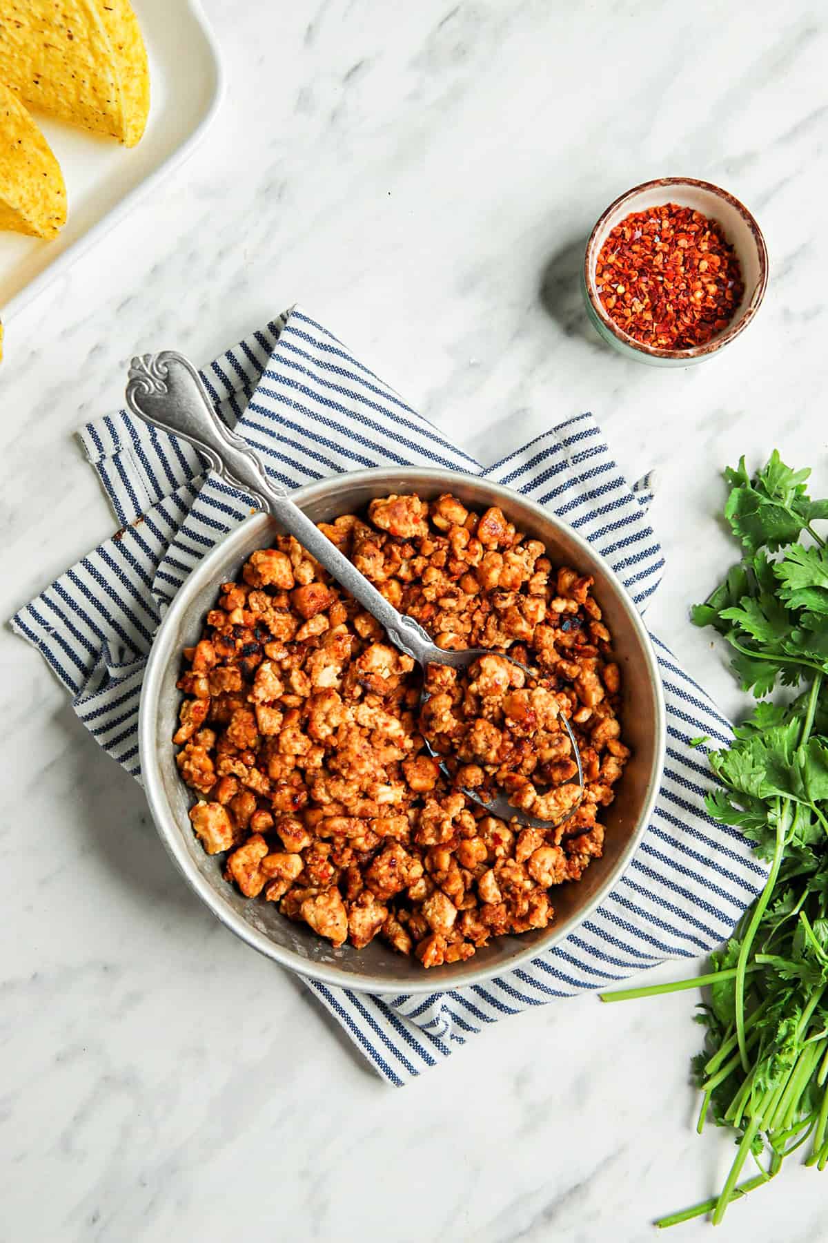 vegan taco meat in bowl with spoon and linen next to fresh herb