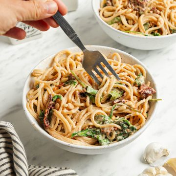 two bowls with hummus pasta and fork