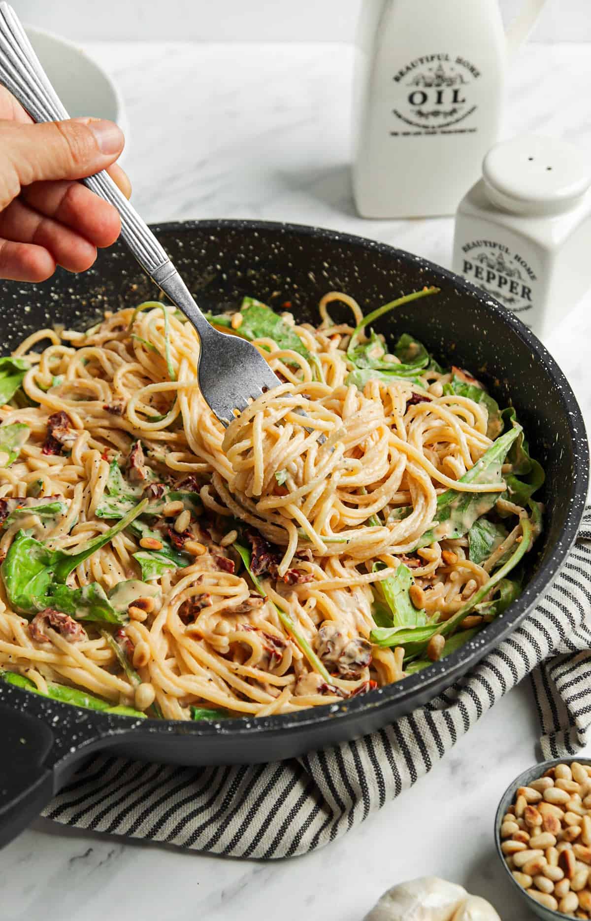 skillet filled with hummus pasta with arugula