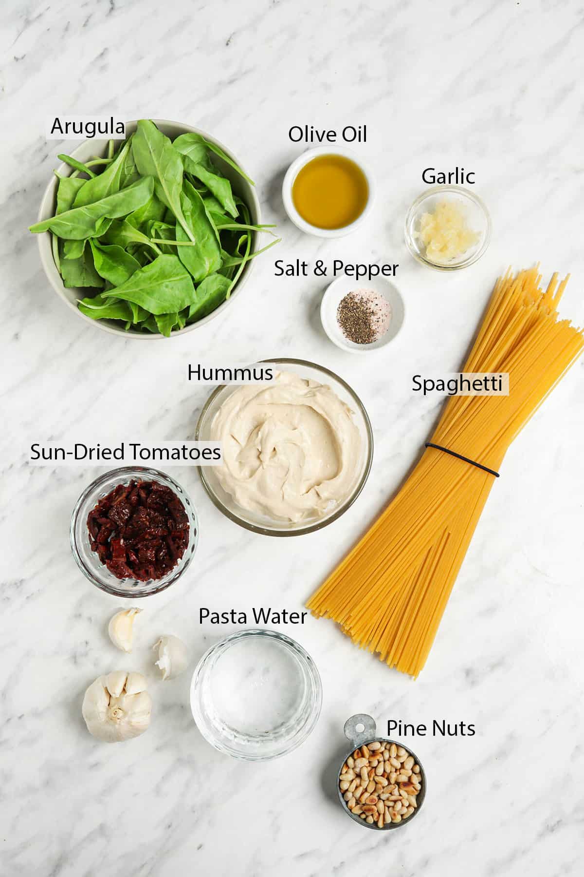 hummus, arugula, salt, pepper, spaghetti, sun-dried tomatoes, pasta water, garlic, olive oil, pine nuts