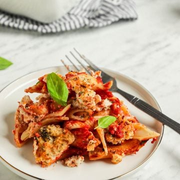 one plate of vegan baked ziti with fork and topped with fresh basil leaves