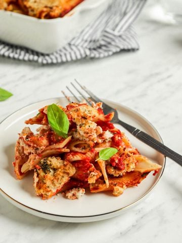 one plate of vegan baked ziti with fork and topped with fresh basil leaves