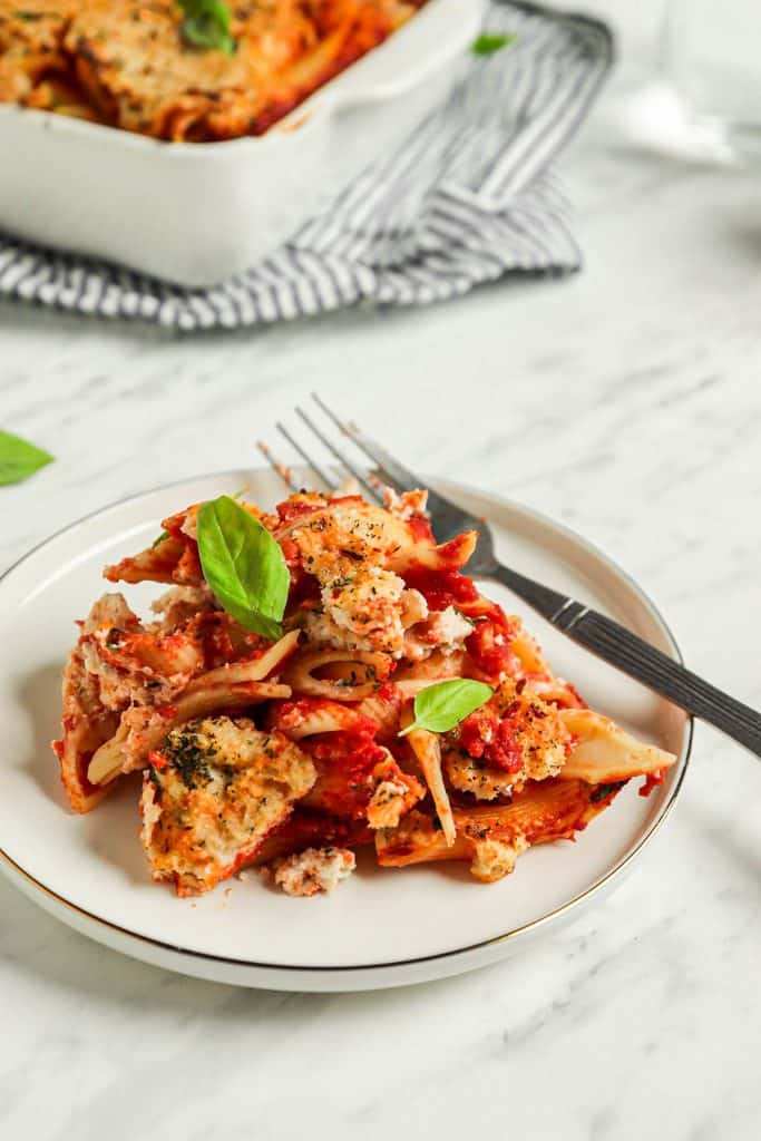 one plate of vegan baked ziti with fork and topped with fresh basil leaves