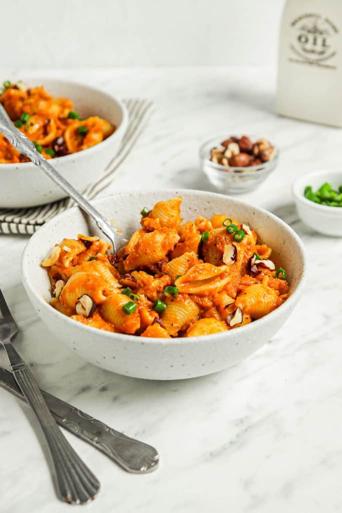 fork in bowl of pumpkin alfredo with hazelnut and green onions