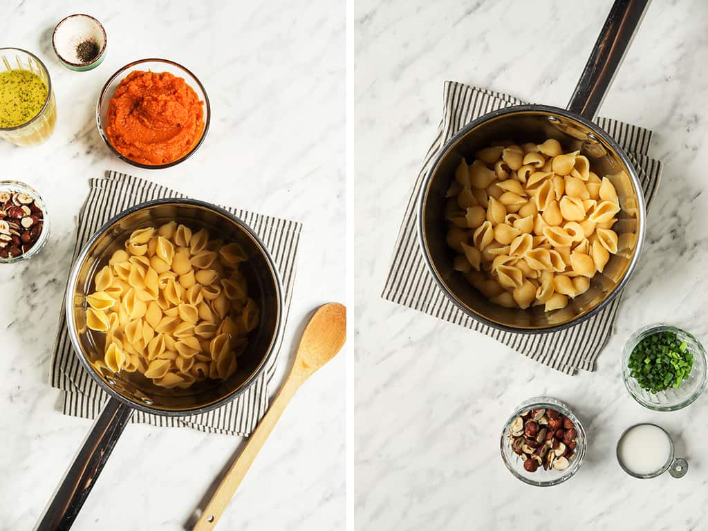 Top view of pasta in silver saucepan with pumpkin puree, veggie broth, salt, pepper, and hazelnuts to the side with chives, milk, and wooden spoon