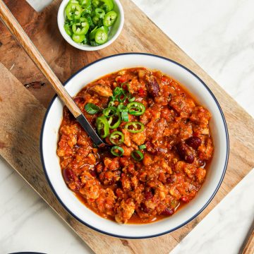 two bowls of vegan pumpkin chili with kidney beans and sliced green onions