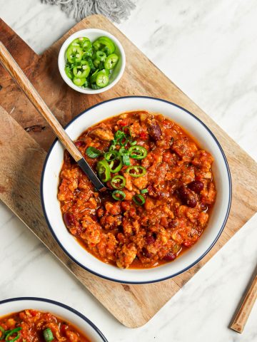 two bowls of vegan pumpkin chili with kidney beans and sliced green onions