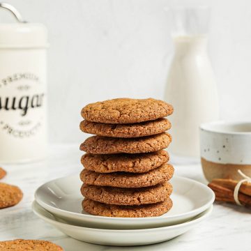 seven cookies in a stack on two white plates with sugar and milk in background