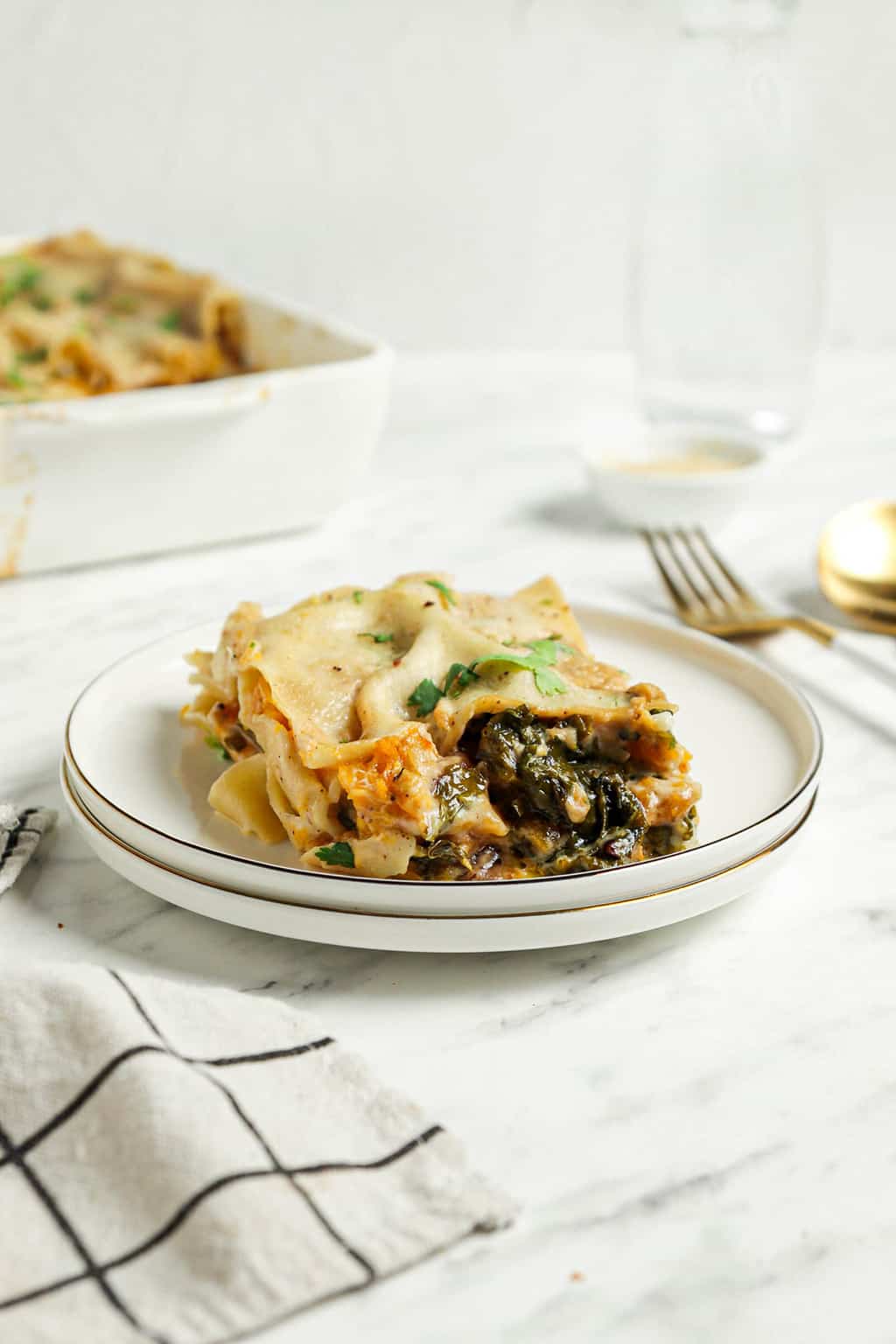 white plate with lasagna butternut squash with bechamel sauce and fresh parsley