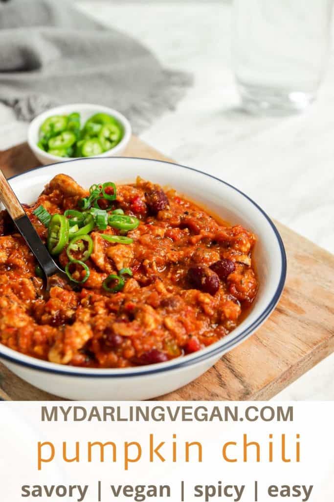 one white bowl filled with vegan pumpkin chili and green onions