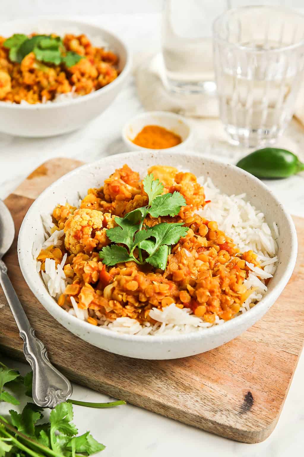 Finished cauliflower curry served over rice in a white board. 