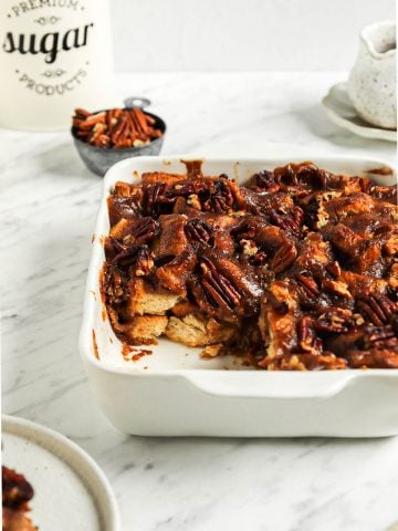 one pan of baked vegan bread pudding with slice taken out of it