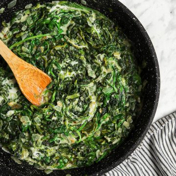 one large skillet with vegan creamed spinach recipe with wooden spoon