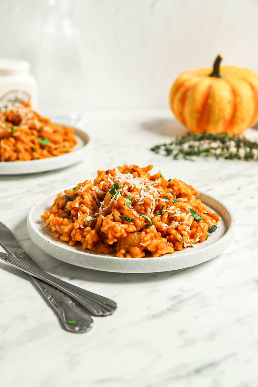 Finished pumpkin risotto on a white plate with two forks.  