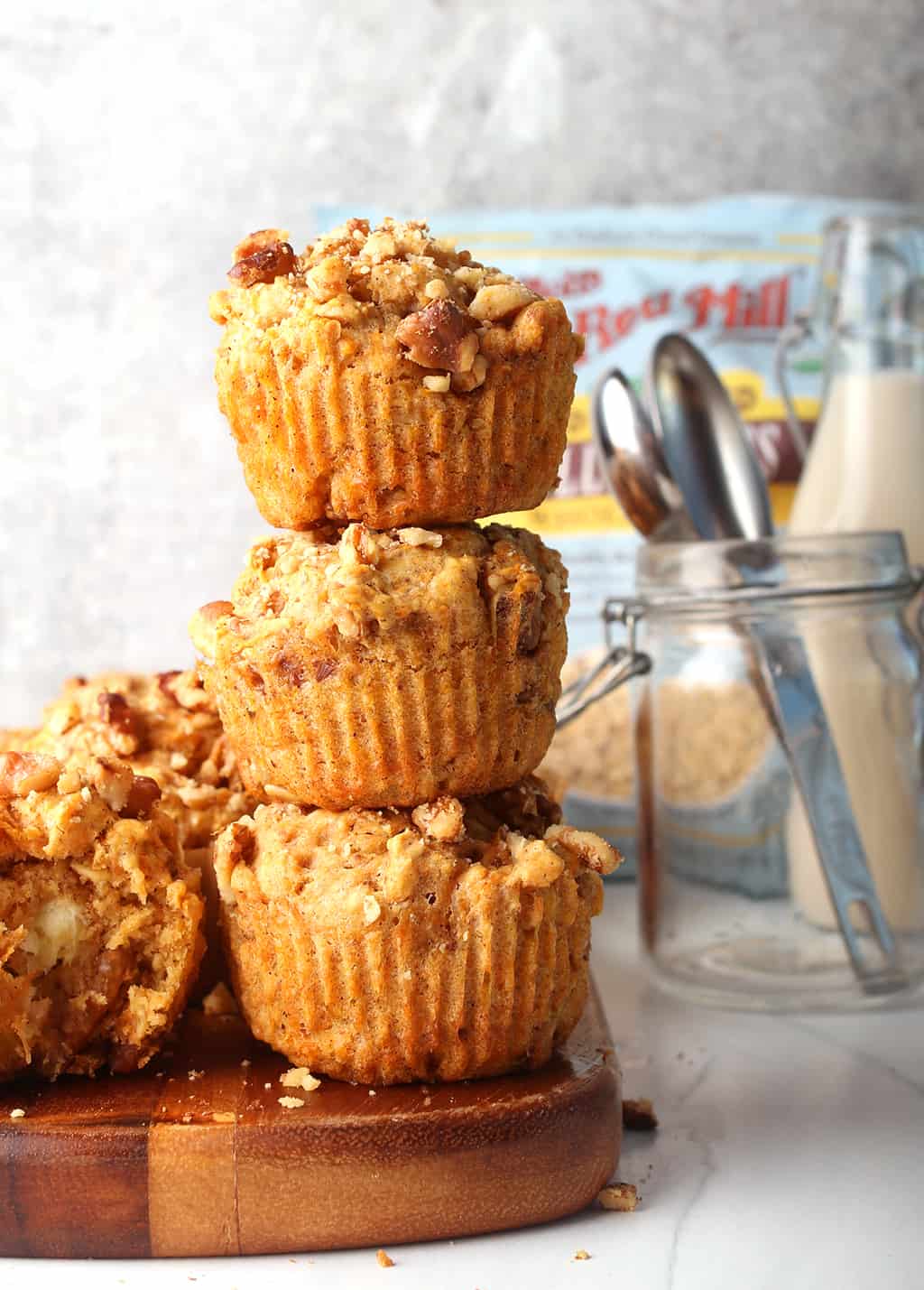 Stack of three finished carrot muffins on a wooden platter