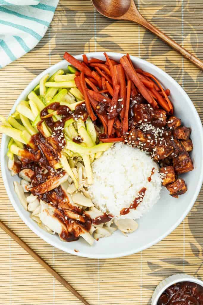 tasty vegan bibimbap bowl with tofu served with chopstick and spicy gochujang sauce