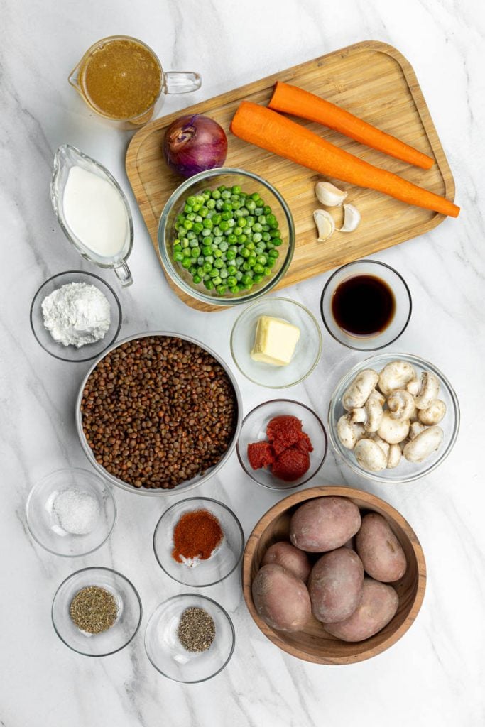Ingredients laid out for vegan shepherds pie with lentils, carrots, and potatoes before cooking