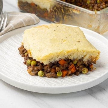 Slice of vegan shepherds pie on a plate with golden mashed potato and savory lentils