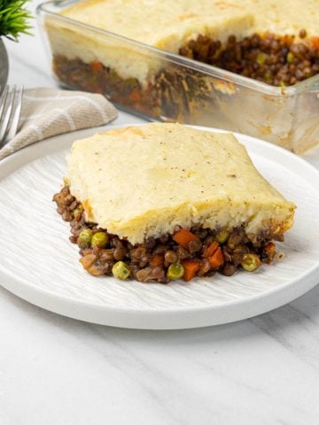 Slice of vegan shepherds pie on a plate with golden mashed potato and savory lentils