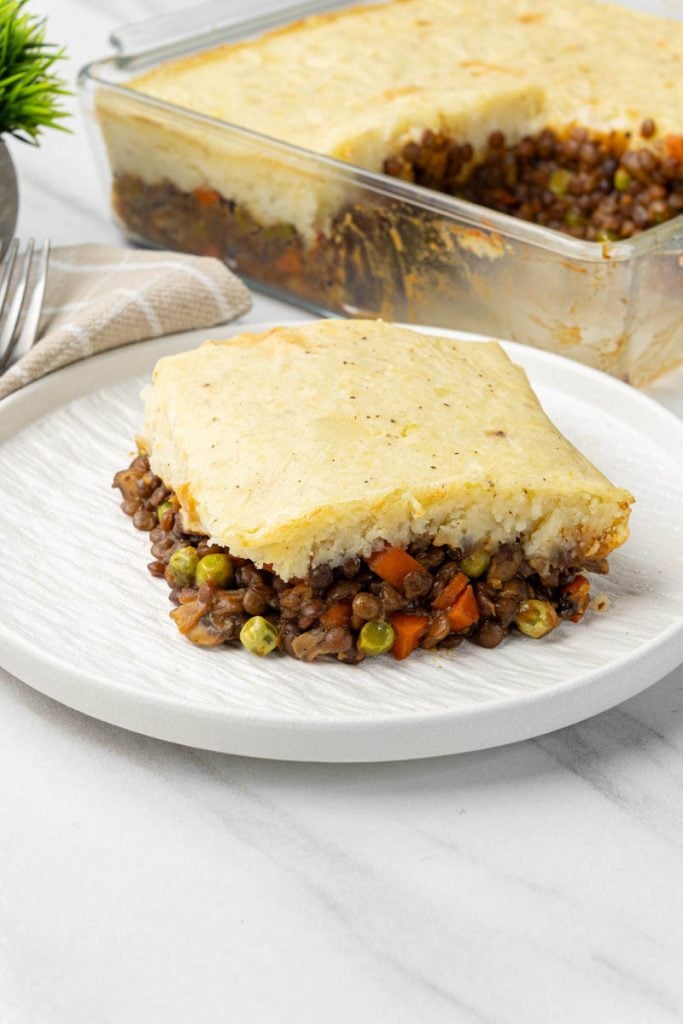 Slice of vegan shepherds pie on a plate with golden mashed potato and savory lentils