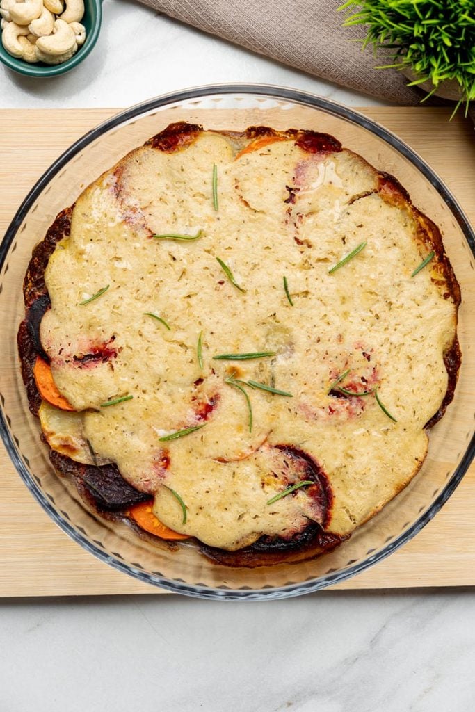 top view of vegan vegetable gratin baked in a glass dish on a cutting board