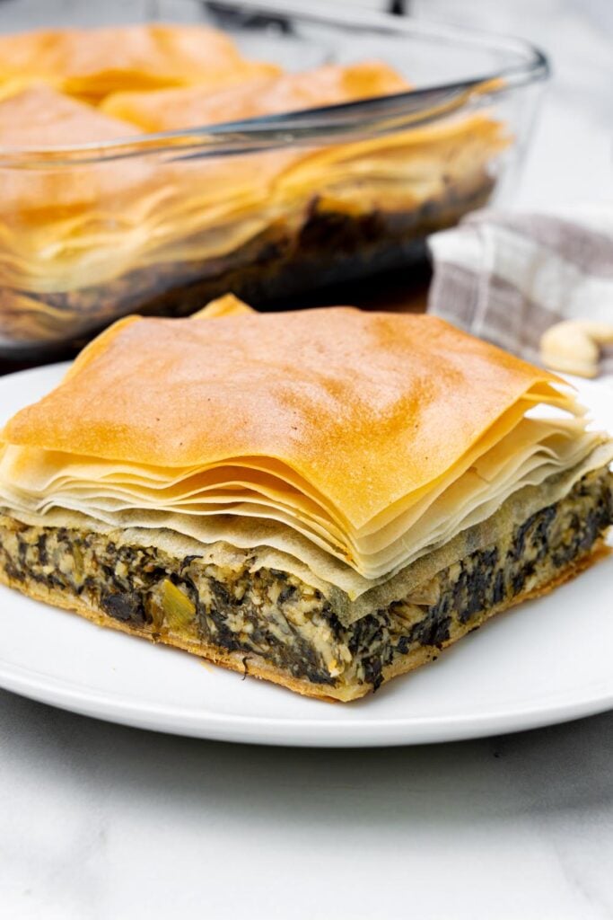 side view of vegan spanakopita with cashew feta, flaky phyllo and thick spinach filling