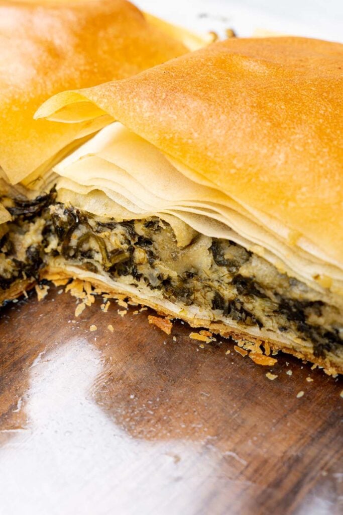 close-ep of sliced Greek spinach pie in a baking dish with flaky phyllo