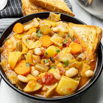 yummy vegan soup with cabbage, potatoes and white beans serves with bread