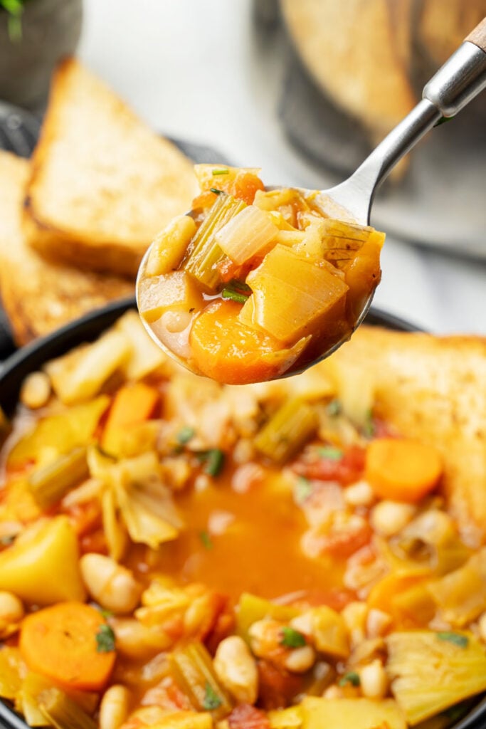 spoonful of vegan soup with cabbage, potatoes, white beans and vegetables