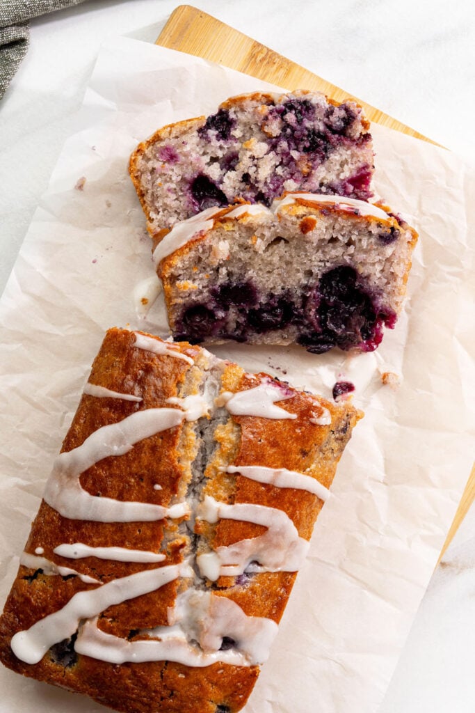 Lemon blueberry loaf with vegan glaze drizzle sliced and arranged showing golden top and moist interior