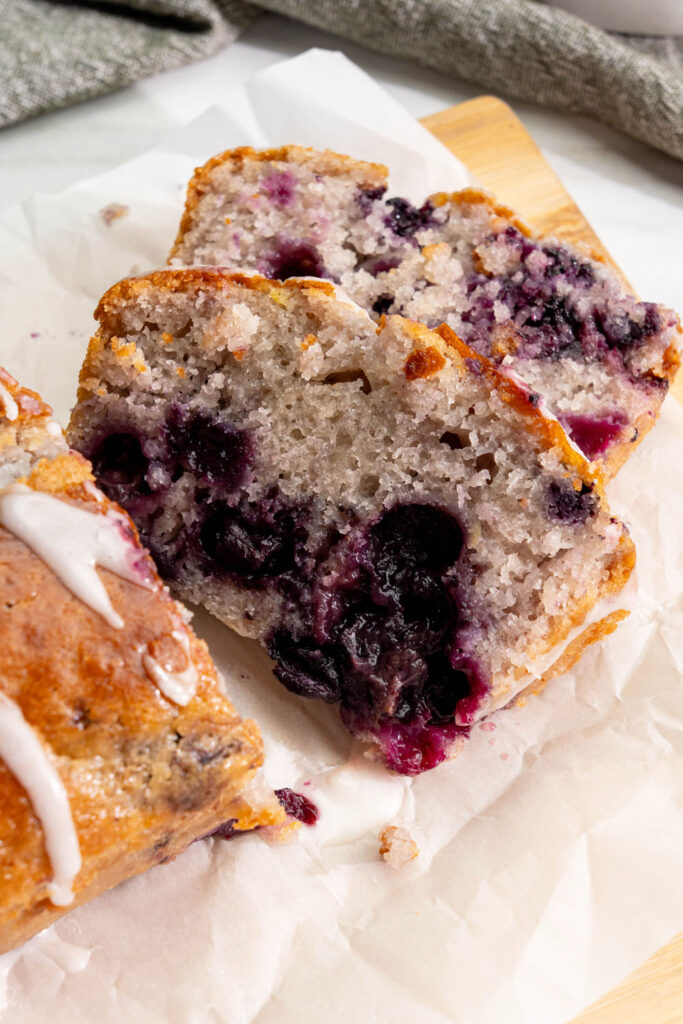 vegan lemon blueberry loaf sliced open showing juicy berries and moist crumb with dairy-free glaze