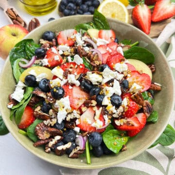 Vegan mixed berry spinach salad with strawberries, blueberries, apples, candied pecans and maple dijon dressing