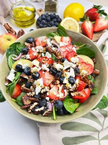 Vegan mixed berry spinach salad with strawberries, blueberries, apples, candied pecans and maple dijon dressing