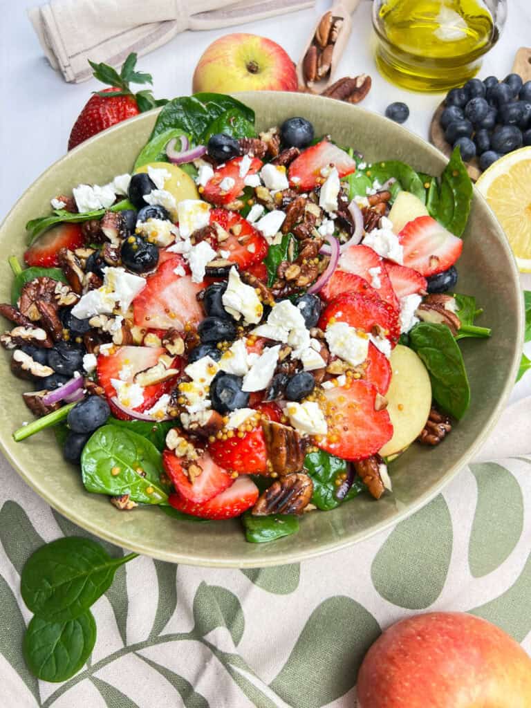 slight angle view of spring spinach salad with berries, red onions, vegan feta and dairy-free dressing