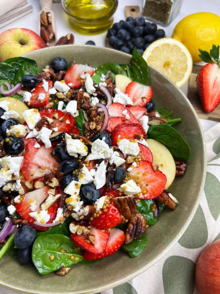 Close-up view of vegan berry salad with juicy fruit, candied pecans and homemade maple dijon dressing