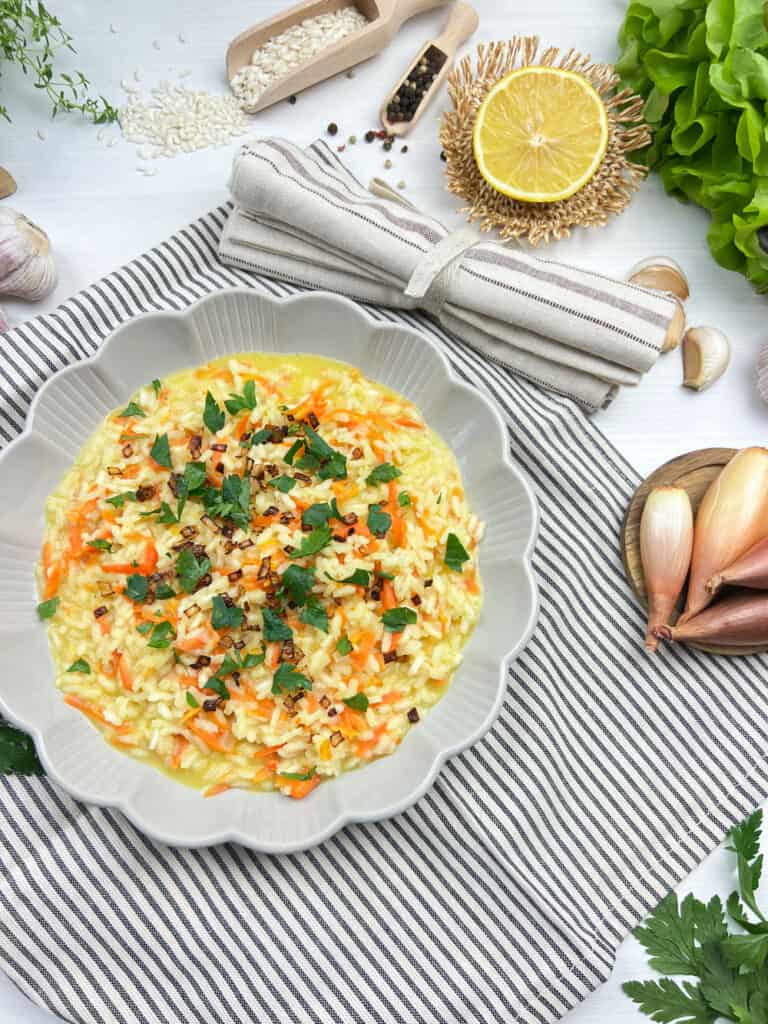 top view of vegan risotto with carrot topped with homemade crispy shallots and lemon
