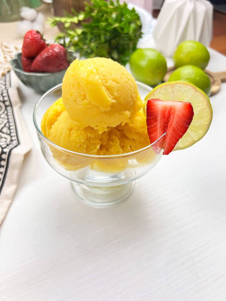 bright and refreshing mango sorbet styled with fresh fruit in a clear bowl
