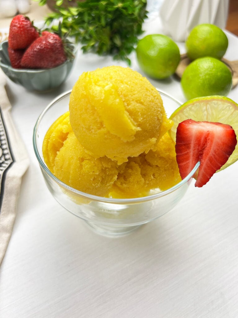 scoops of finished mango sorbet served in a bowl with fresh fruit garnish
