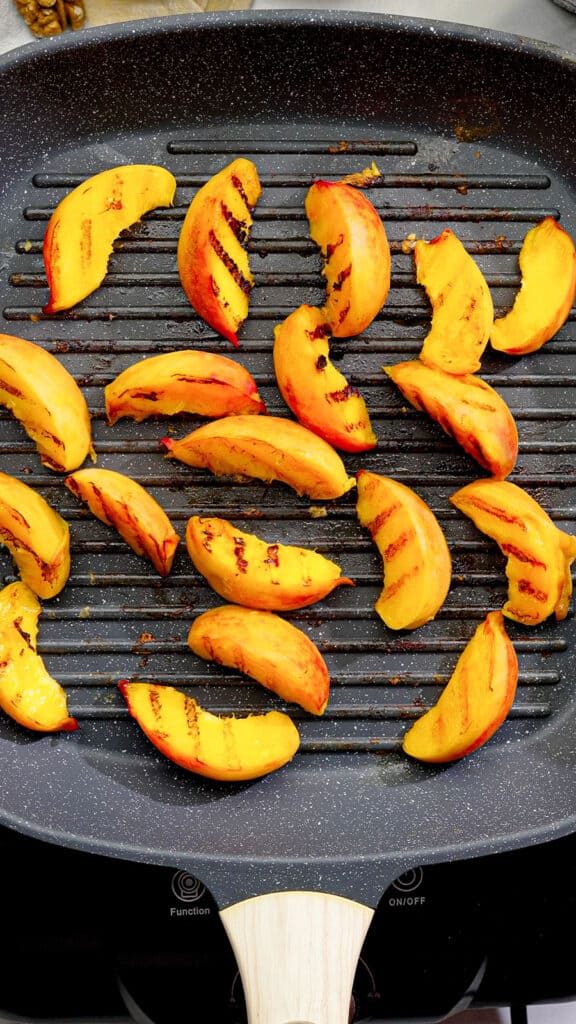grilling peach slices in a pan for a vegan salad with whipped vegan feta