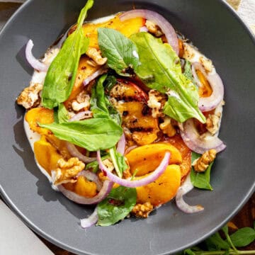 grilled vegan peach salad with basil, walnuts and red onion sitting on dairy-free whipped feta