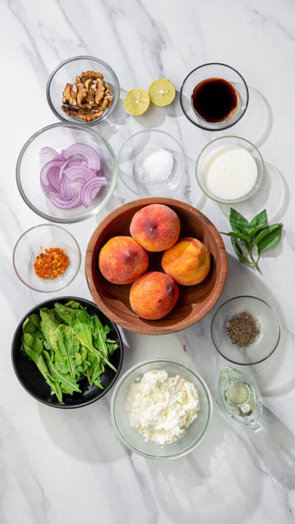 ingredients for grilled peach salad with vegan feta, arugula, basil, red onion, walnuts and balsamic dressing