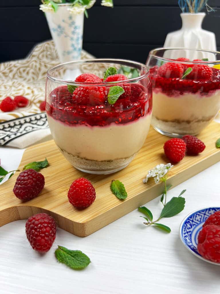 Layered vegan raspberry cheesecake with graham crust, creamy filling and homemade berry compote