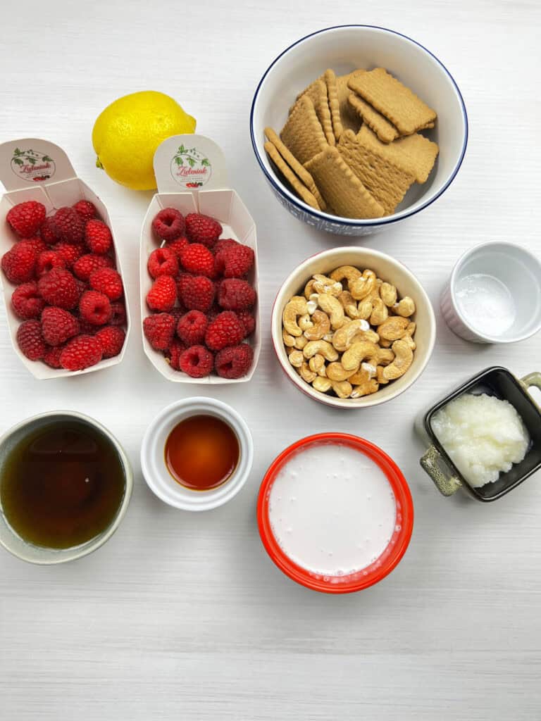 ingredients for vegan cheesecake cups including berries, cashews, graham crackers, coconut milk and syrup