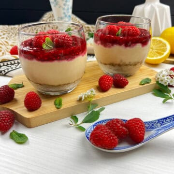 No-bake raspberry cheesecake cups with a creamy cashew filling, graham cracker crust, and berry compote