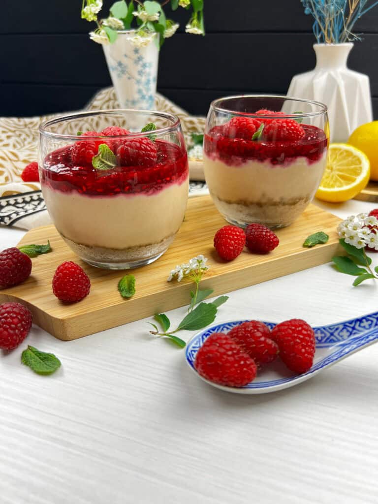 No-bake raspberry cheesecake cups with a creamy cashew filling, graham cracker crust, and berry compote