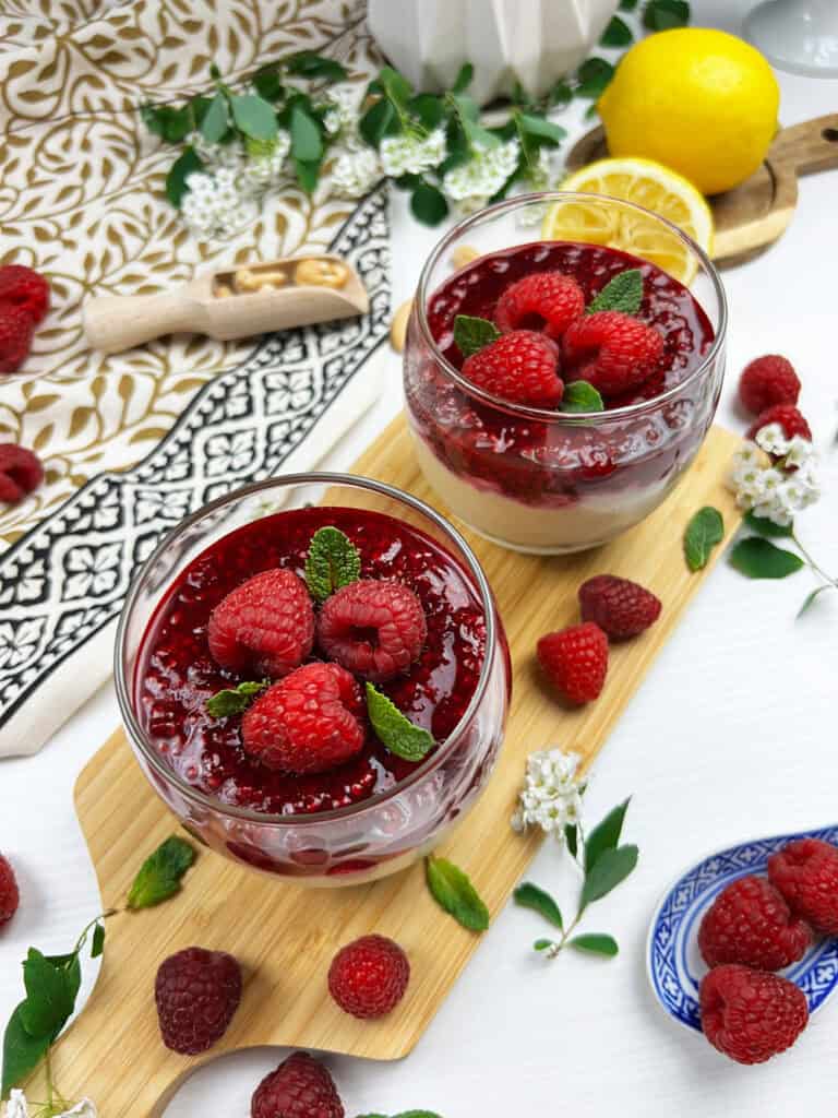 Creamy vegan cheesecake desserts topped with raspberry compote, fresh berries and mint leaves
